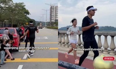Runner with a headband jogging across a street while spectators watch from the sidewalk, with Indonesian caption about a Putrajaya–Salak Tinggi route (left).